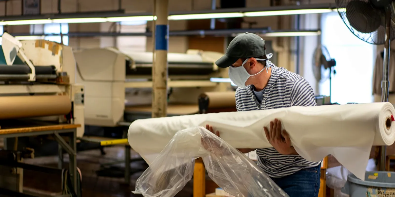 Worker handling a roll of fabric in a textile factory
